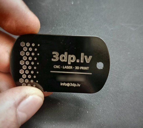 The same tag in hand — for scale